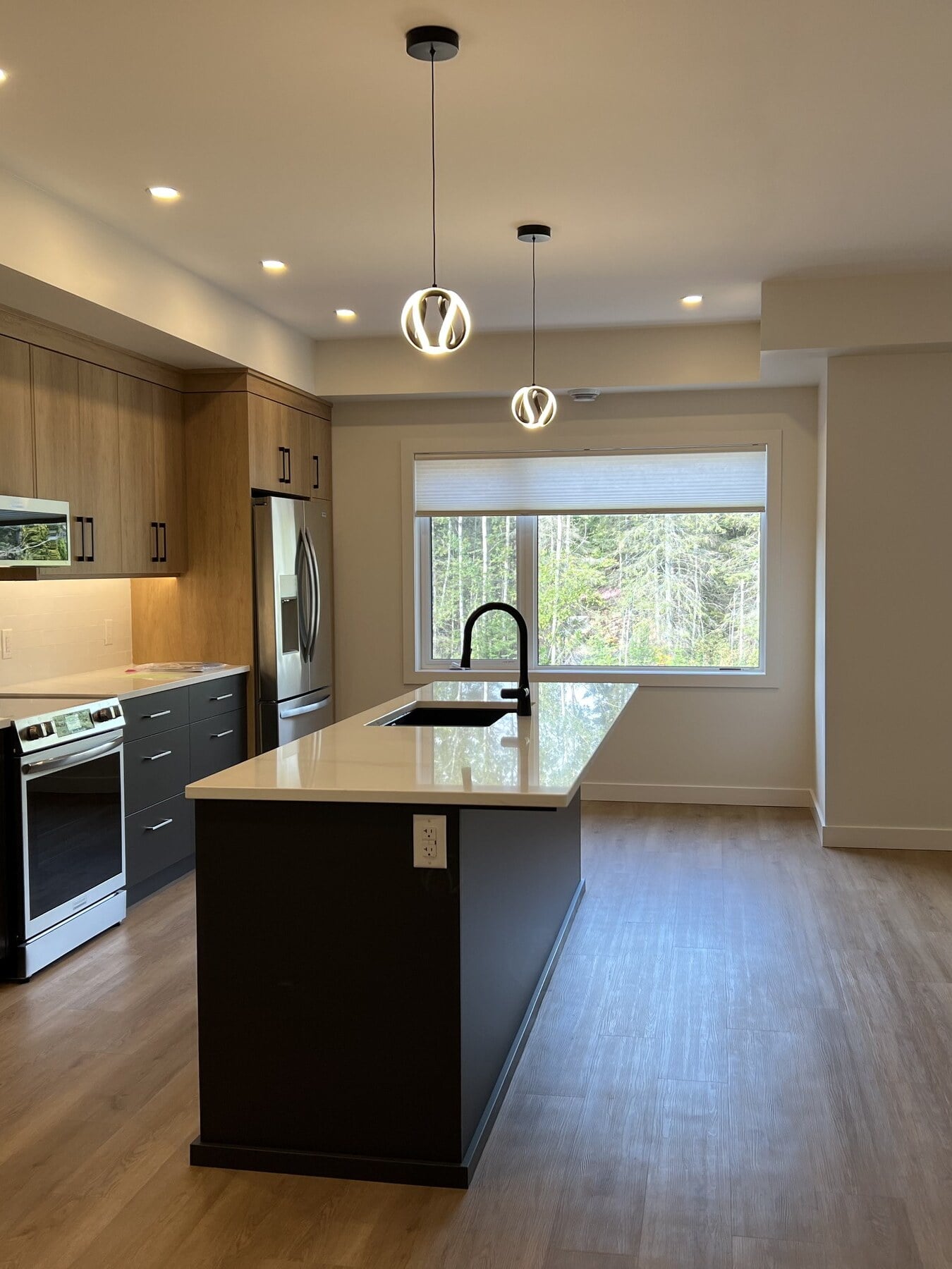 Kitchen with island, range and wood cabinetry looking toward the living area